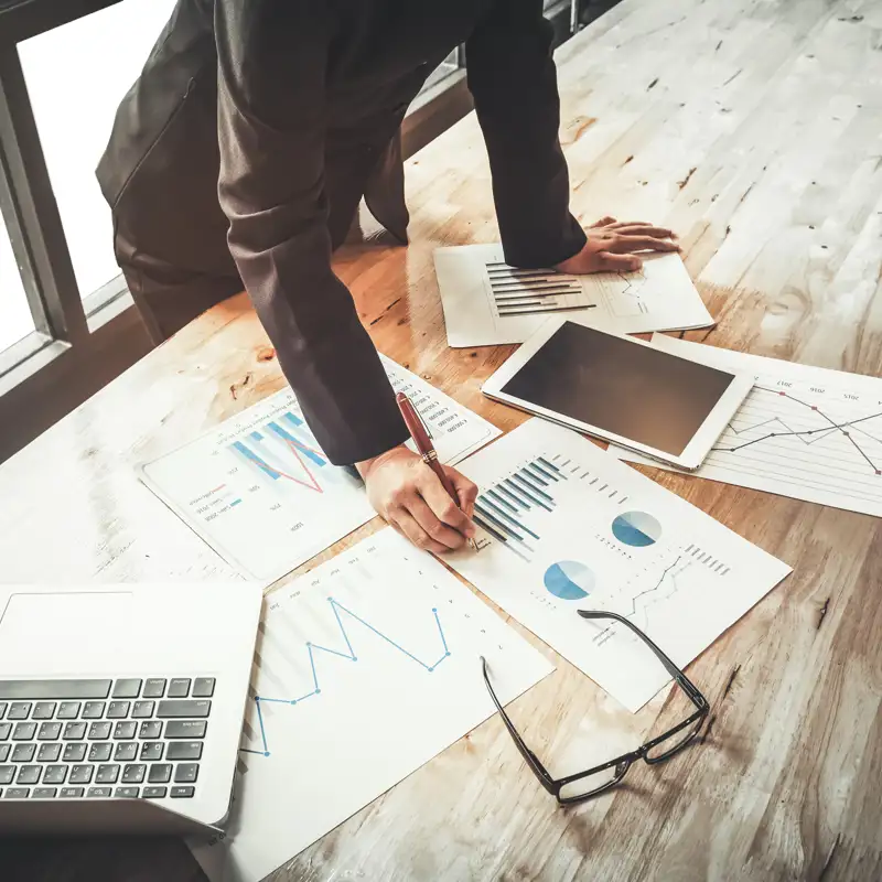Investment consultant analyzing company annual financial report balance sheet statement working with documents graphs.
